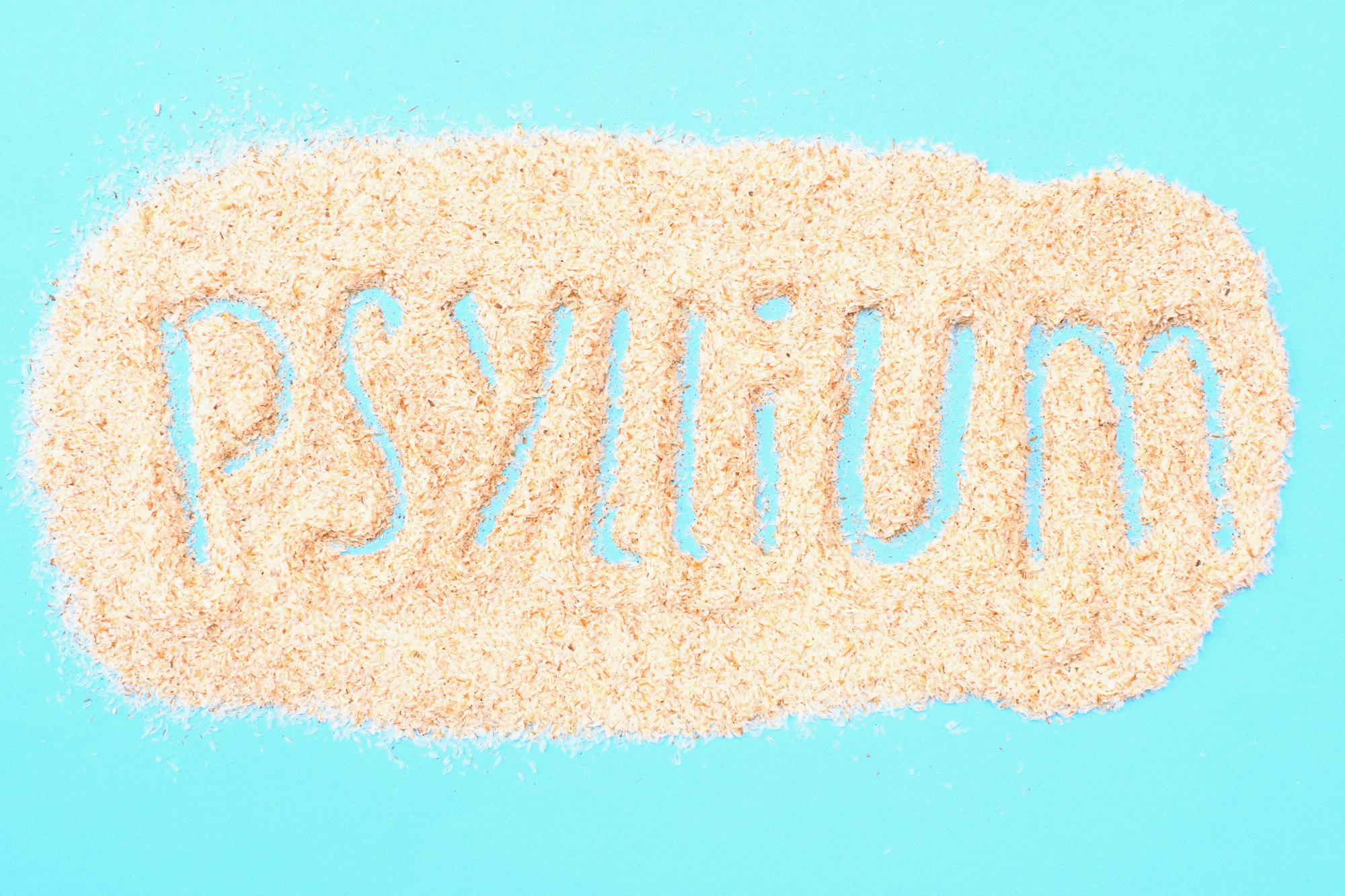 Psyllium inscription on plantain husks close-up on blue background.